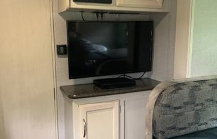 30" TV with cable connection/Aerial antenna, remote, DVD player/Radio, Storage space next to radio and underneath TV. Trailer temperature control is next to the TV on the left.