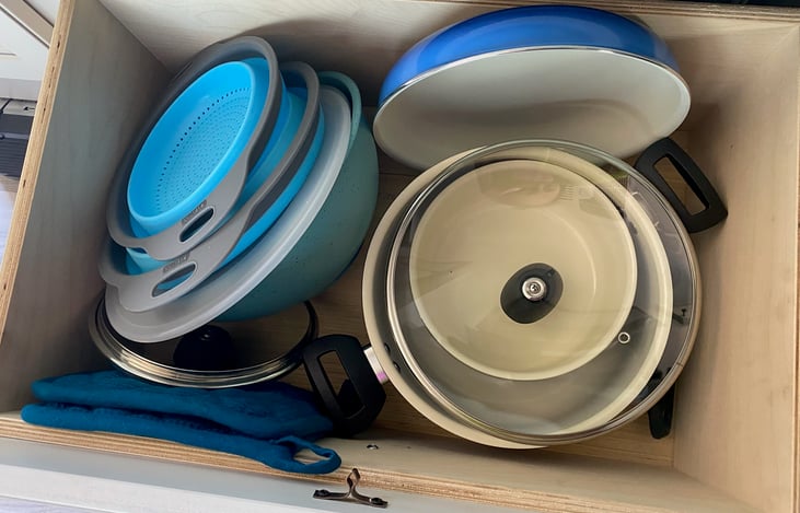 Stocked with pots, pans, mixing bowls and serving pads.