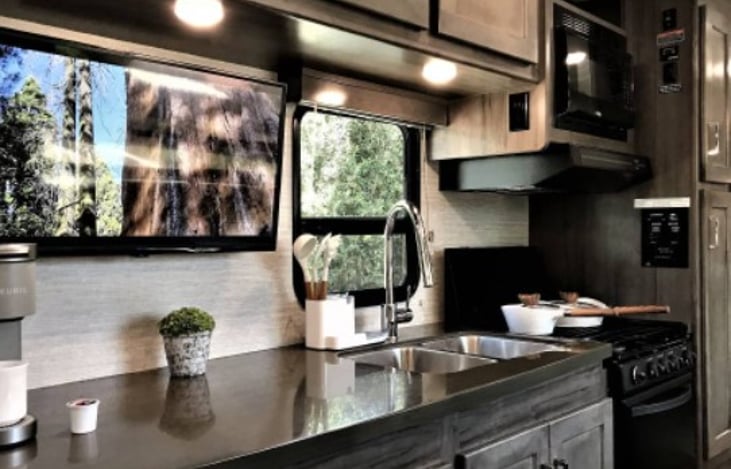 Kitchen, including double sink, microwave, range, stove and range hood that vents outside the cabin