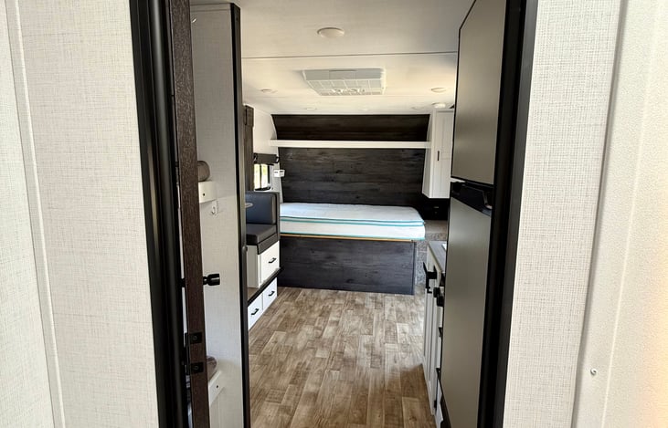 Looking from the rear bathroom toward front of RV with slide open. Tall ceilings, wide living space, XL dinette for four adults.