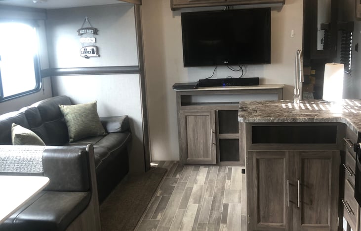 Standing in front of the double sized bunk beds.  Horseshoe dinette and jacknife couch to the left (converts to double bed).  TV, DVD player, AM/FM Bluetooth Soundbar forward.  Kitchen sink to right