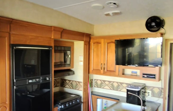 The Hot Tub Suite kitchen has a refridegerator, freezer, microwave, stove, oven, an ice maker, and a smart TV