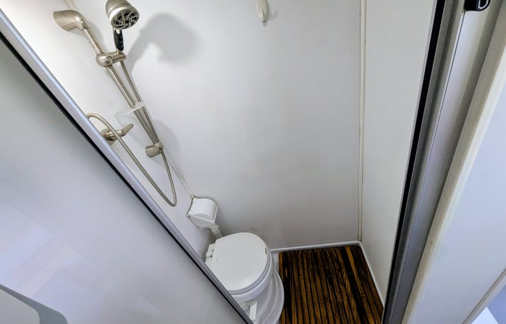 Full wet-bath with shower, toilet and teak floor mat.