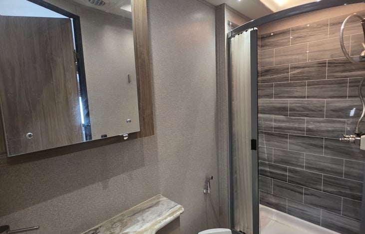 Modern full bathroom with residential-style shower, vanity sink, and toilet. Please note: Use only RV -safe toilet paper