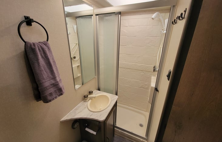 Bathroom Shower, Sink and Vanity Mirror. Hand towels.