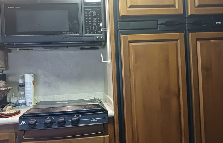 microwave, Stove and Refrigerator behind the wooden door