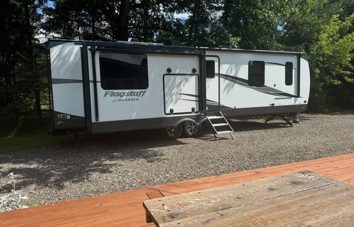 Outdoor kitchen next to entrance on left slide along with two awnings expanding the length of the camper.