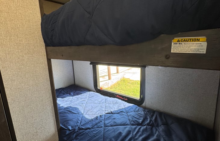 Comfortable twin size bunk beds. The mattress is thick and comfortable unlike most RV cushions. We provide a mattress cover and comforter. No pillows. The bottom bunk features a window that opens.
