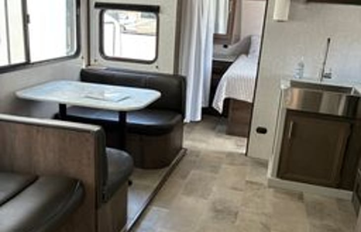 A roomy kitchen featuring a farmhouse sink, microwave, stove, and refrigerator with freezer space. There's ample room for dining, enjoying a cup of coffee, playing games, or cozying up with your favor