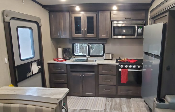 Fully stocked kitchen with window, microwave, stove and oven along with lots of storage space