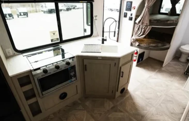 Stove, microwave, sink and a view of the bunkbed