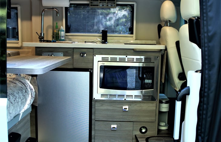 Kitchen area. Convection oven, microwave, fridge, and storage.