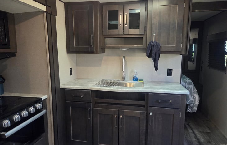 Single Basin Kitchen Sink with Faucet. RV Equipped with silverware, plates, cups and cooking utensils.