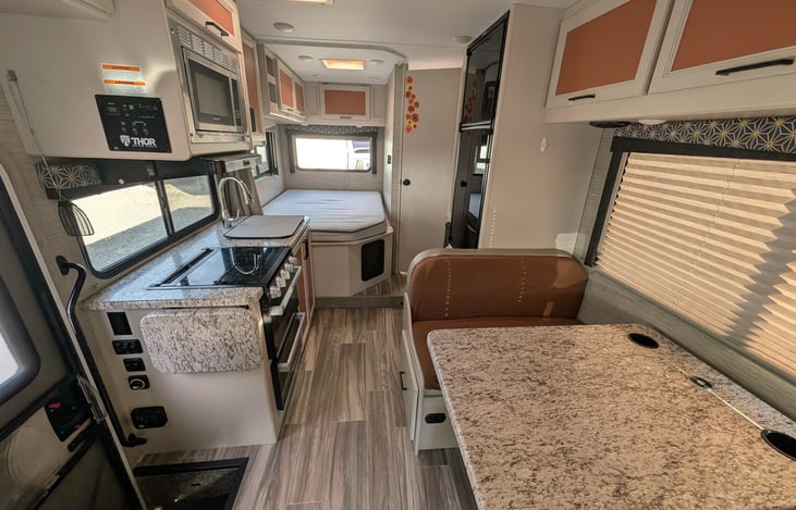 Bright, modern interior with a cute pop of color! Features a cozy rear queen bed, fully equipped kitchen, converting dinette, over-cab bunk, and an accent armchair. Clean, open, and ready for adventur
