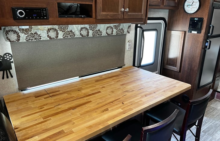 Seating for three at the bar with a TV that raises and lowers.  TV has been lowered into the bar to allow more counter space.