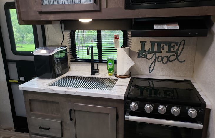 Kitchen has a 3 burner stove with vent hood, oven, microwave, ice maker and large sink