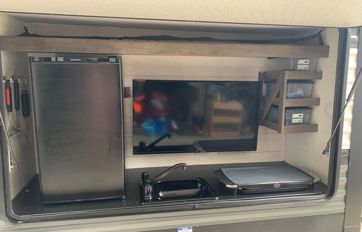 Outdoor kitchen ft. 40" smart TV, fridge, flat top, sink and swing-out propane grill