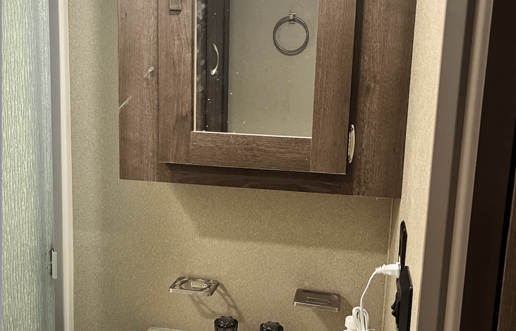 Sink with under cabinet. Cabinet above with mirror.