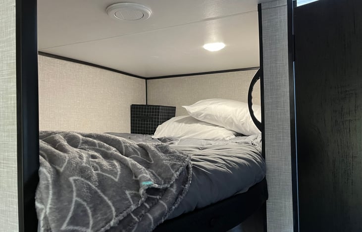 Top bunk, full size (300lb capacity)has sheet protector, bedding, two pillows, individual lighting and a storage cubby.