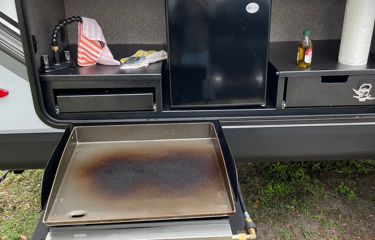 Outdoor kitchen with mini fridge and Blackstone grille.
