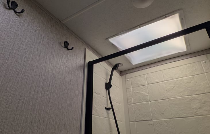 Shower has a sky light. Shower head can be turned on and off at the head in order to save water.