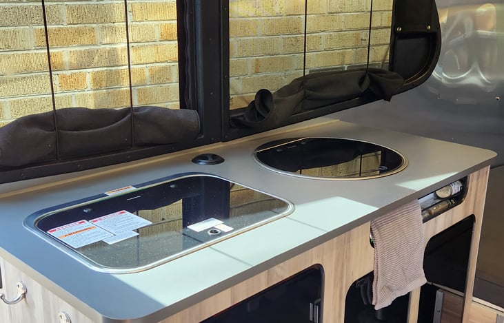 A full kitchen is ready to host all of your meals. The Airstream Basecamp 20X features a 2-burner propane cooktop, sink, refrigerator and microwave.