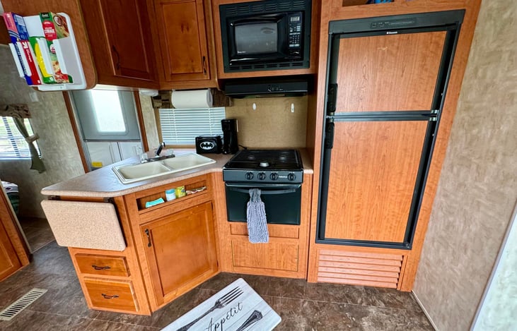 Kitchen with fridge, freezer, microwave, stove top, and oven. Kitchen also includes plastic bag storage, all cooking/eating utensils, coffee maker, toaster, mini waffle maker, & spices/seasonings.