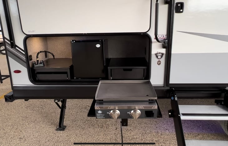 Outdoor kitchen with griddle and fridge.