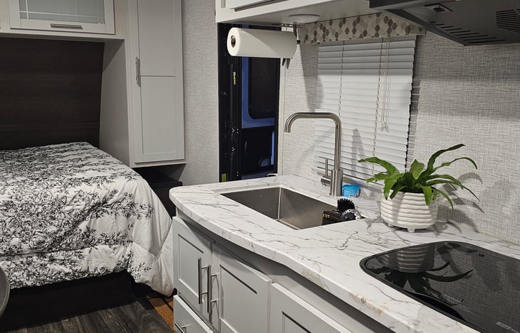 Kitchen with sink, stove and microwave. Cooking pans and cooking utensils stocked.