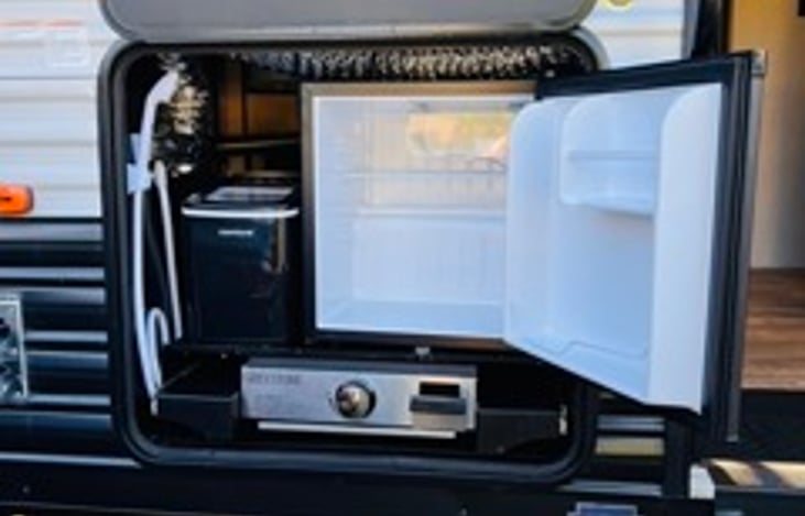 Outside kitchen with refrigerator and grill. There is also an outdoor shower.