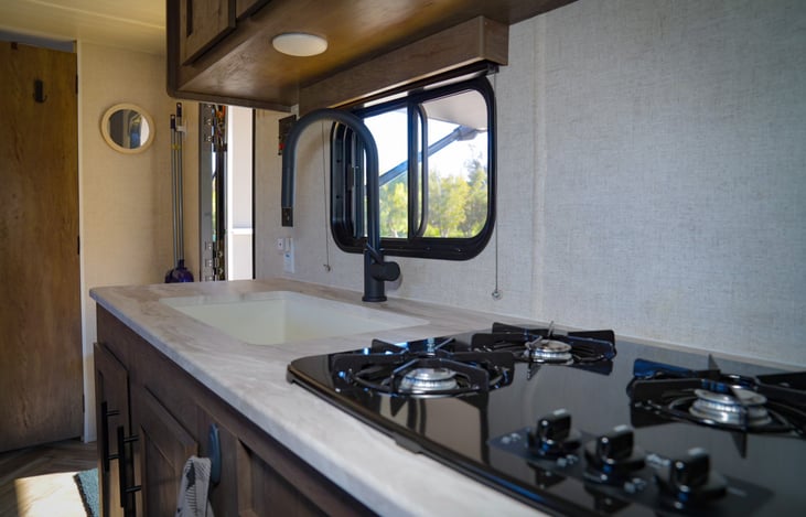 a 3-burner stove and farmhouse sink with pull down faucet provide all of the luxuries of home.