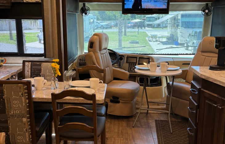 Can seat 6 for meals using using  Captain chairs & collapsible table. Captain chairs swivel 180 degrees. The passenger seat also reclines and front dash includes a small pull-out desk w/ plug below