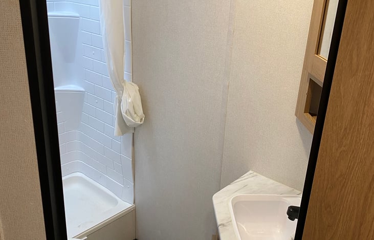 BATHROOM INCLUDES TOILET, STANDUP SHOWER, AND SINK WITH STORAGE ABOVE AND BELOW