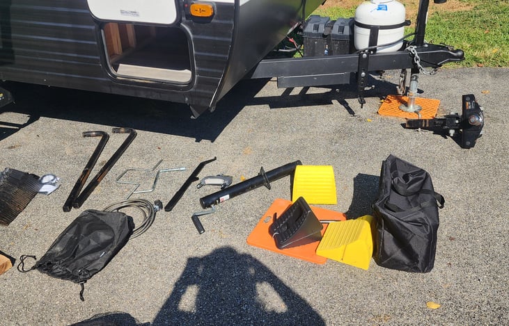 Tow hitch w/sway bars, wheel chalks (yellow), jack foot pads (orange), leveling blocks (black bag).