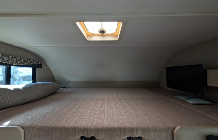 Bright, modern interior with a cute pop of color! Features a cozy rear queen bed, fully equipped kitchen, converting dinette, over-cab bunk, and an accent armchair. Clean, open, and ready for adventur