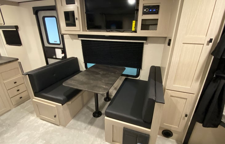 Dinette with thermofoil pedestal table, under bench storage with easy access door and entertainment center with LED TV