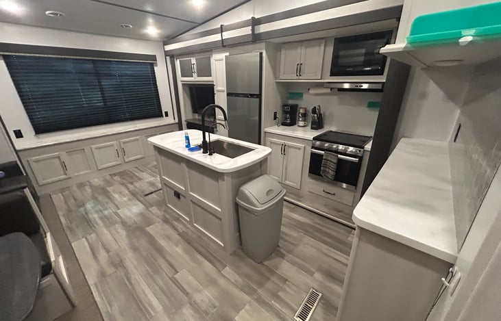 Stocked kitchen with pots and pans, dish-ware and utensils for 4, and coffee maker.