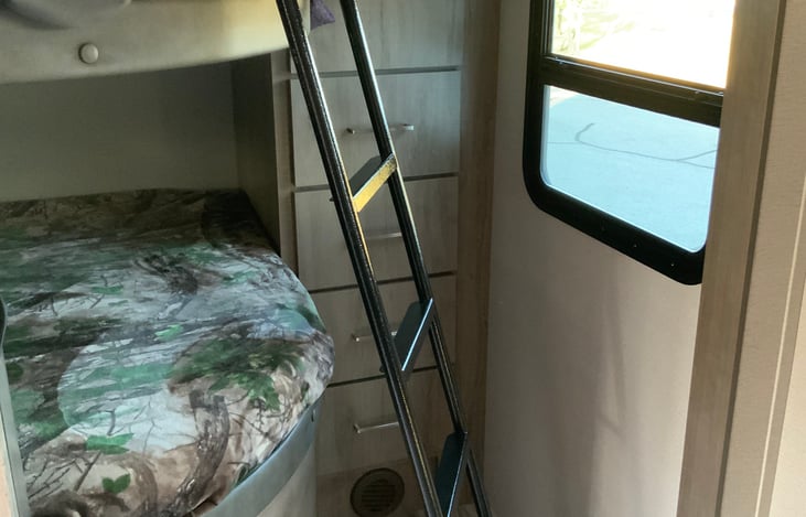 Bunk beds at the back of the RV have a sliding door for privacy and 4 drawers and 2 shelves for storage.  ladder included for top bunk