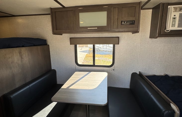 Dinette features a window that opens for a nice breeze to flow through. All windows have blinds for privacy. The dinette turns into a twin size bed. Top cabinets provide ample storage and a Bluetooth.