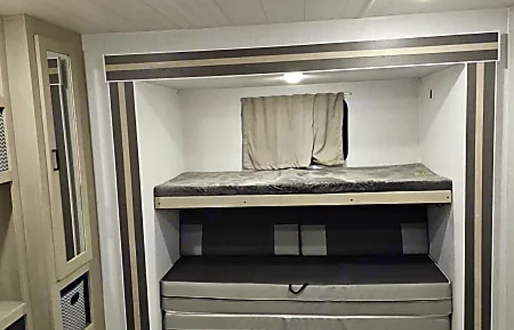 Rear bedroom (right side): Top bunk folded down with the sofa below.