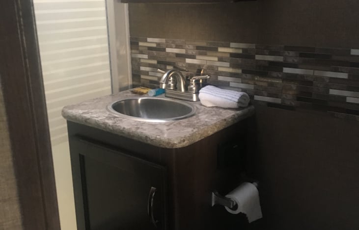 Bathroom with medicine cabinet, toilet , sink and shower. Also included is body wash, shampoo, conditioner, bar soap, toilet paper, bug spray, sunscreen.