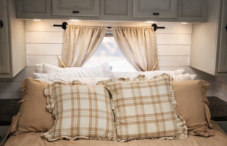 Peaceful private bedroom featuring a comfortable bed, overhead storage, and soft natural light.