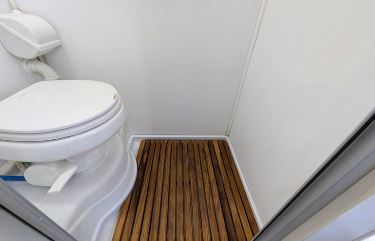 Full wet-bath with shower, toilet and teak floor mat.