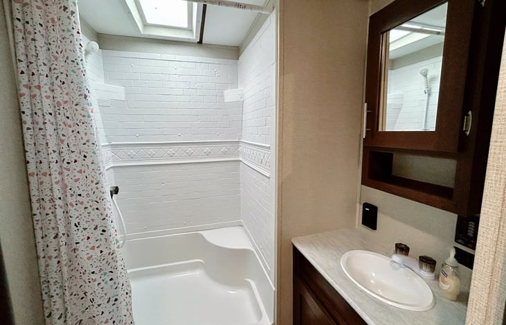 Full sized shower with skylight in a spacious bathroom.