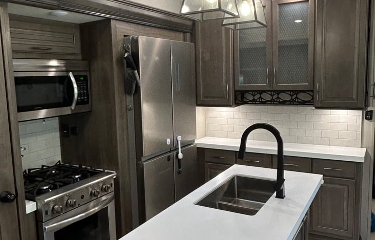 Kitchen sink on island with ample counter space and storage.  There are multiple smoke detectors and CO detectors throughout as well as a fire extinguisher stored under sink.