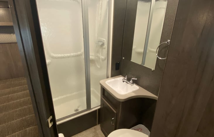 Bathroom (stall shower, sink, toilet, mirror and medicine cabinet/storage). RV safe toilet paper provided.