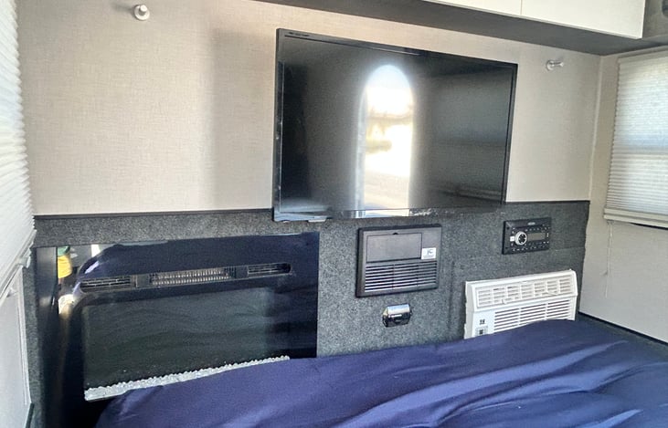 Electric fireplace for heat with adjustable temperature setting, smart TV, bluetooth stereo with indoor and outdoor speakers, and AC.