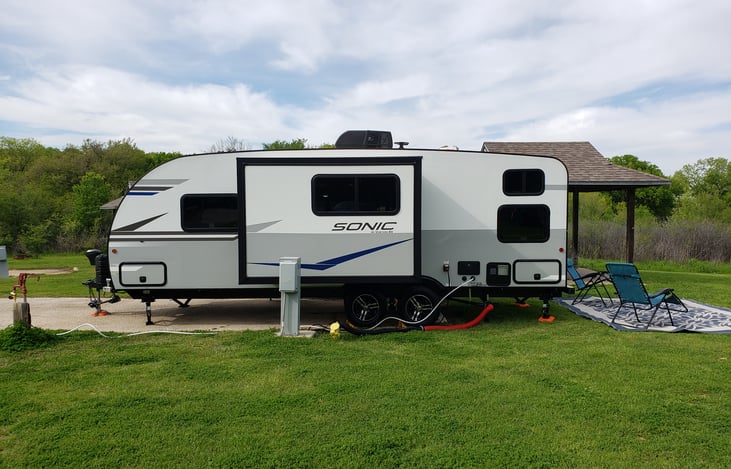 The driver side of the travel trailer has a slideout, outdoor shower, shore power 30amp hook up, public water hookup, and waste tank drain hookup