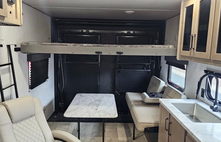 Flexible living area with overhead bunk