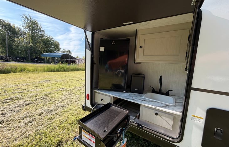 Outdoor kitchen has a second fridge, hot and cold water sink, Ice Maker and griddle.